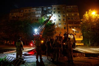 Firefighters work outside a damaged multi-storey residential building, following what local Russian-installed authorities called a Ukrainian military strike